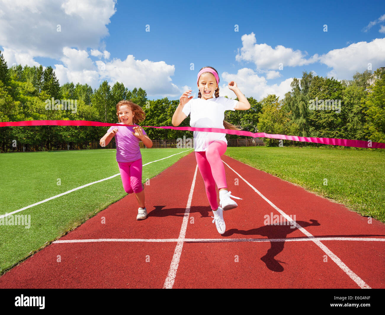 Girl runs and reaches ribbon excited to win Stock Photo