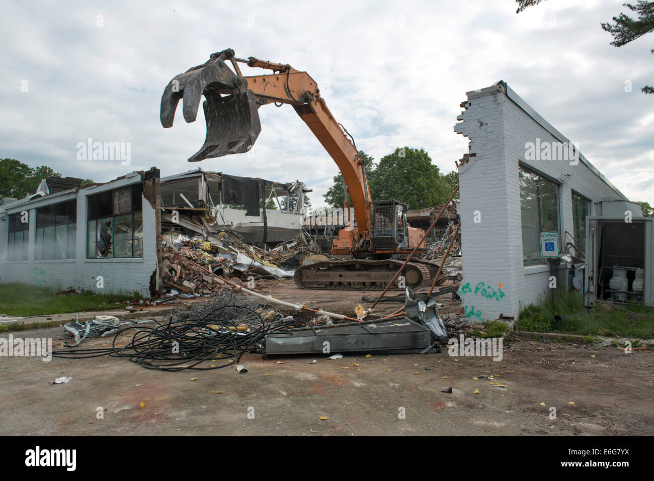 Excavator with grapple doing demolition work on office building in Norwalk, CT.  Materials sorted for recycling. Stock Photo