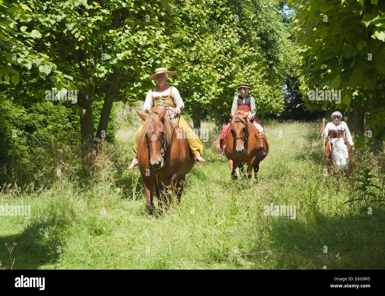 Two 16th century women riding horses and one walking alongside in the English countryside. Stock Photo