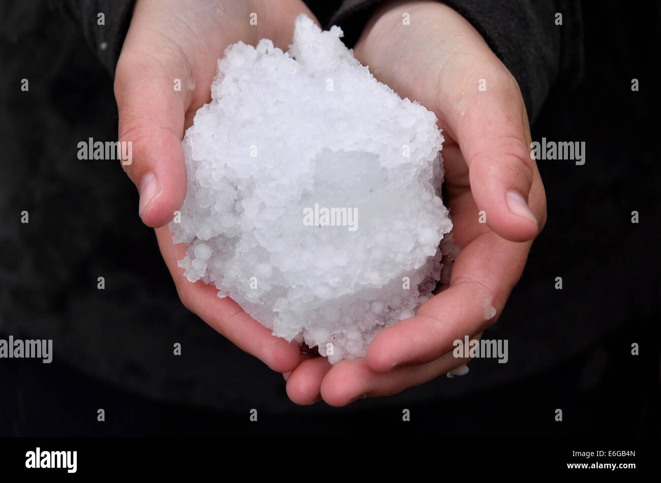 Human hands holding a ball of hail Stock Photo