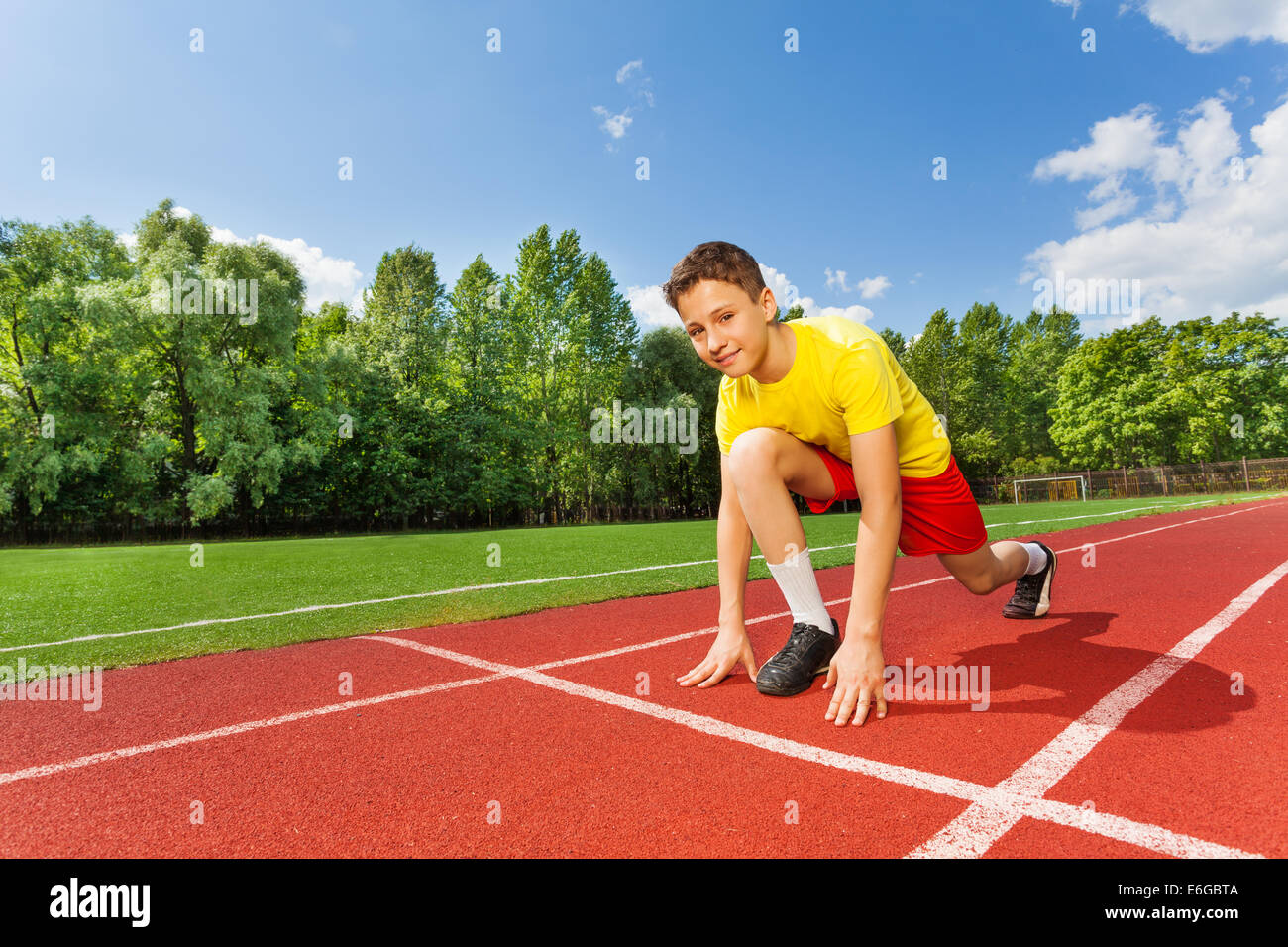 Boy in ready position on one bend knee to run Stock Photo