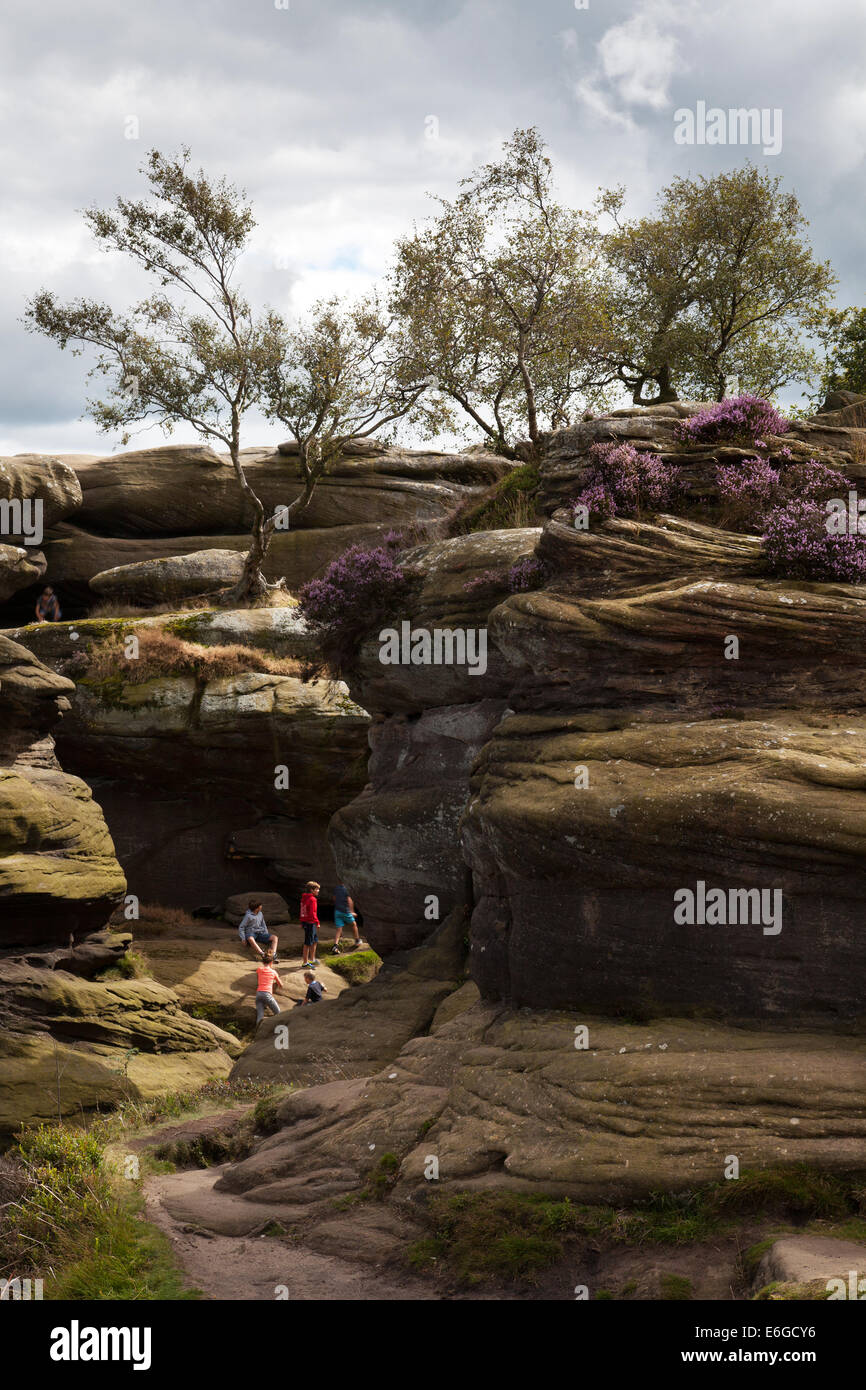 People at Brimham Rocks; Brimham Crags a collection of balancing natural rock formations sculpted over centuries by ice, wind and rain in the North Yorkshire Dales. holidaying active kids and visiting tourists at the National Trust Site making a great day out for families and climbers enjoying  a peculiar set of rock formations composed of millstone grit shaped by wind and weather Stock Photo