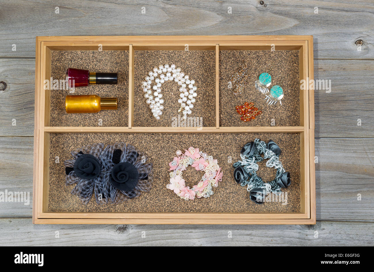 Top view of storage drawer with woman accessories consisting of ear rings, pearl necklace, hair scrunchies, and nail polish Stock Photo