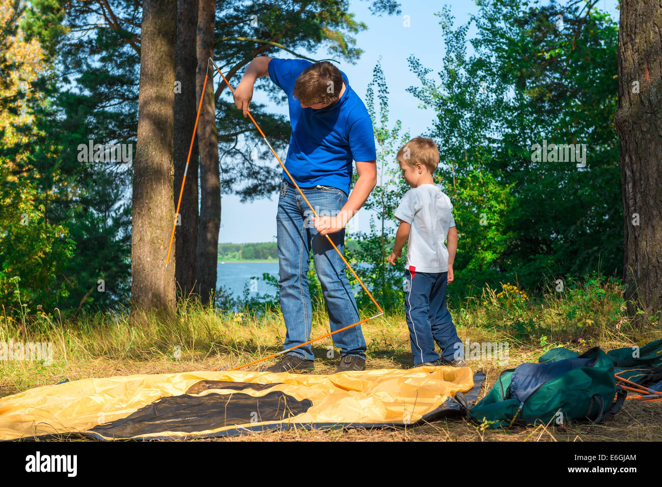 father and son set the tent on the lake Stock Photo