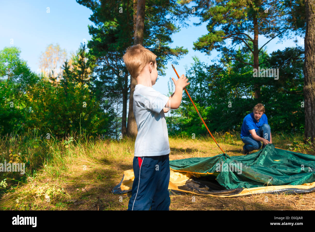 little son helps to establish a tent on the nature Stock Photo