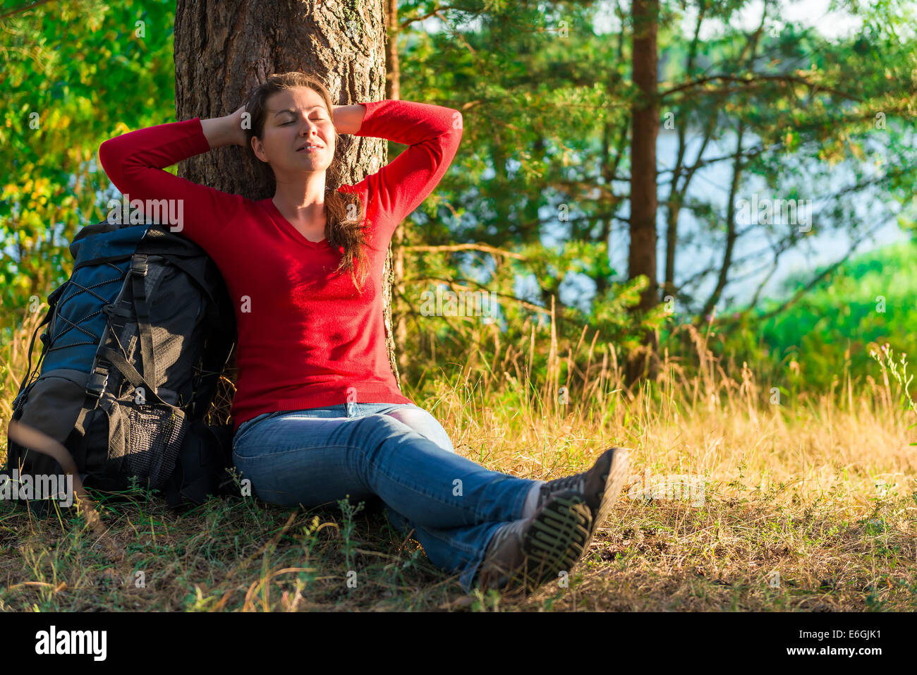 strongly weary backpacker resting against a tree Stock Photo