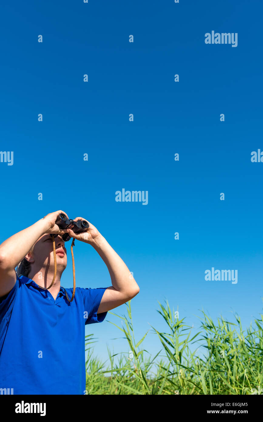 man looking through binoculars into the sky Stock Photo