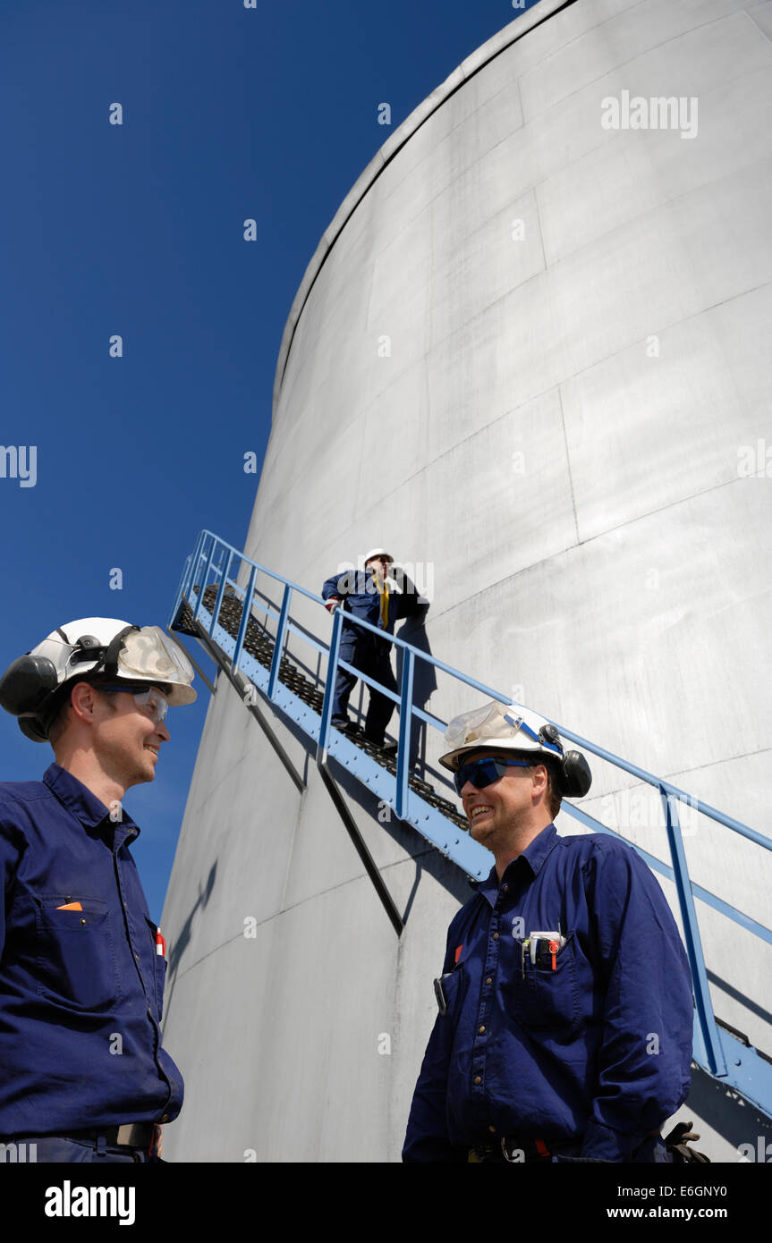 oil and gas engineers with storage tanks in background Stock Photo