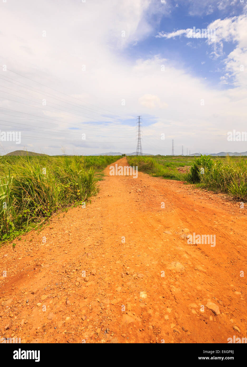 This red soil unpaved road leads us into the middle of nowhere. Stock Photo