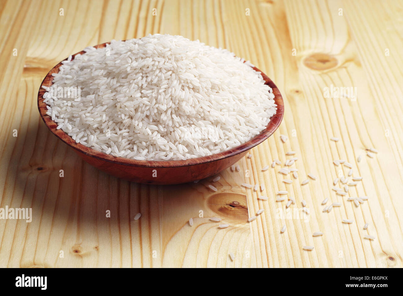 Raw white rice in bowl on yellow wooden table Stock Photo