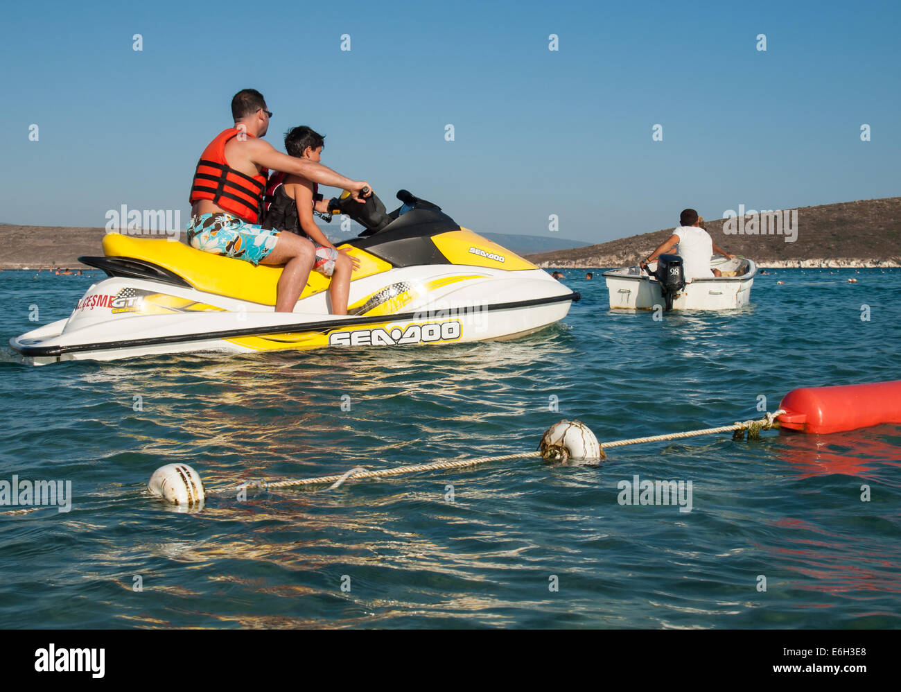 tourists on jet ski passing through boating lane between roped off swimming areas on the cesme coast Stock Photo