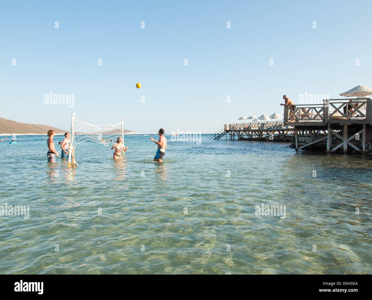 tourists playing volleyball in the shallows on the  coast of the cesme peninsula on the turkish aegean coast Stock Photo