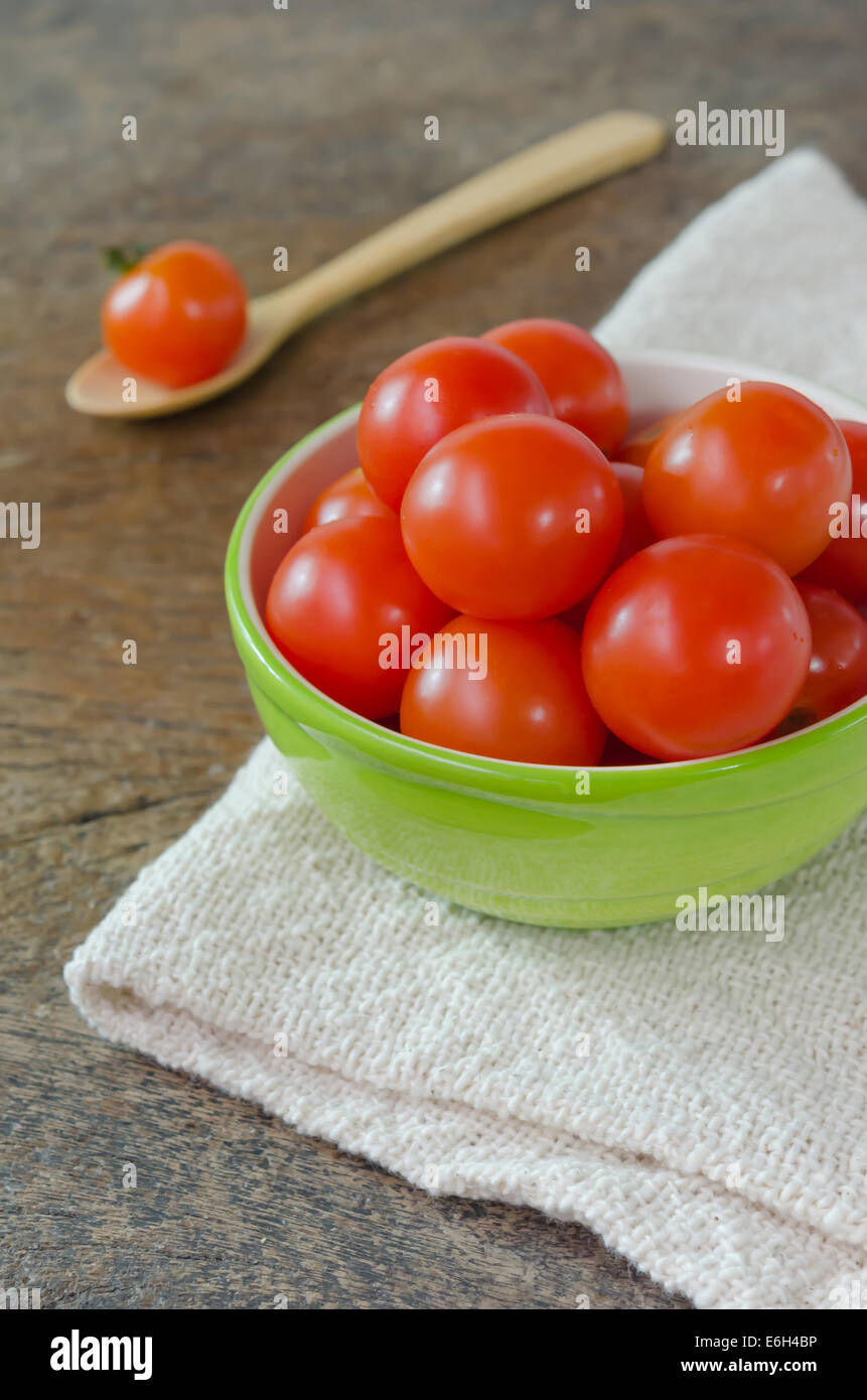Red cherry tomatoes in green bowl and wooden spoon Stock Photo - Alamy
