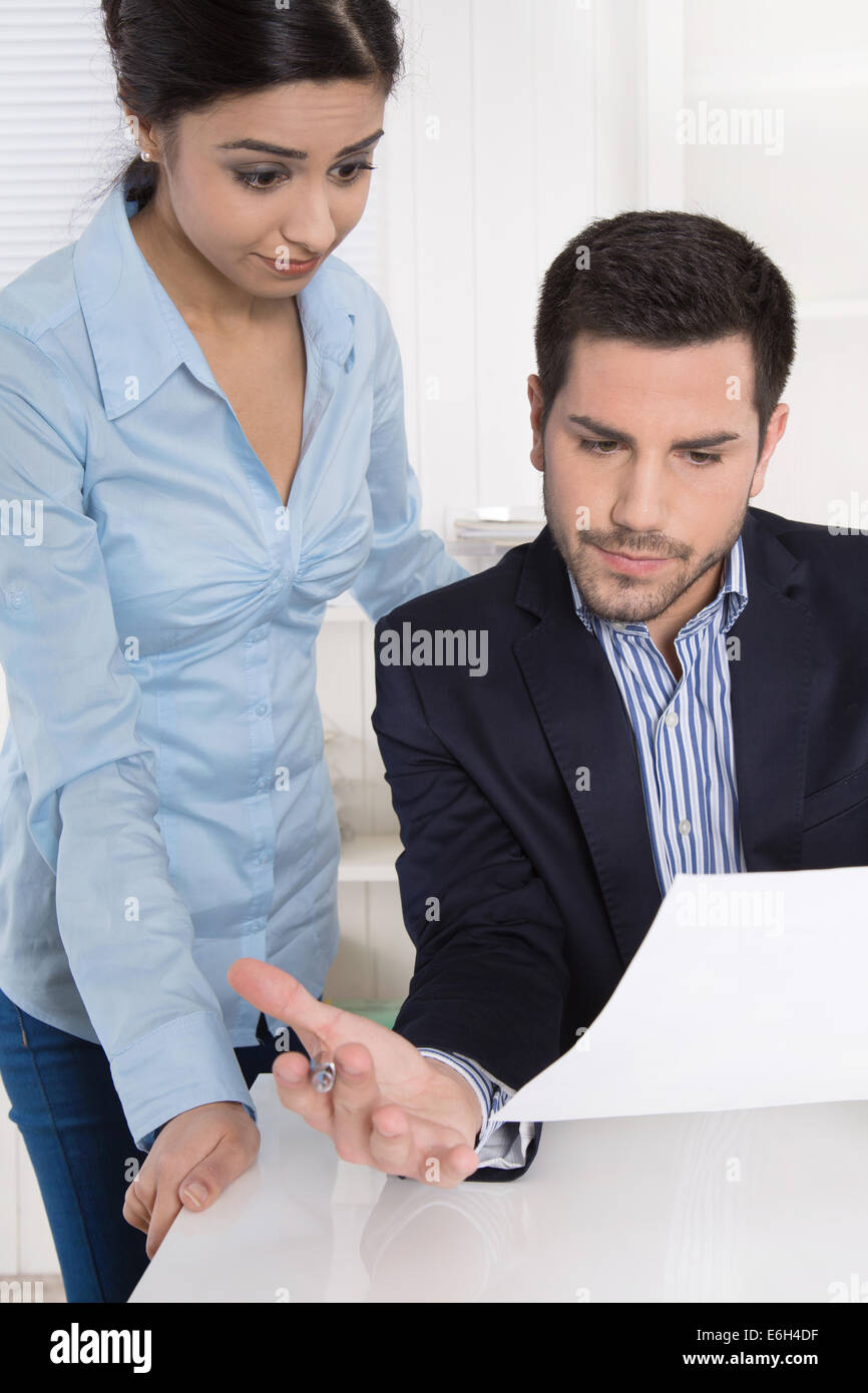 Problems at work: Boss criticizes his female colleague and blame her because of her mistakes. Stock Photo