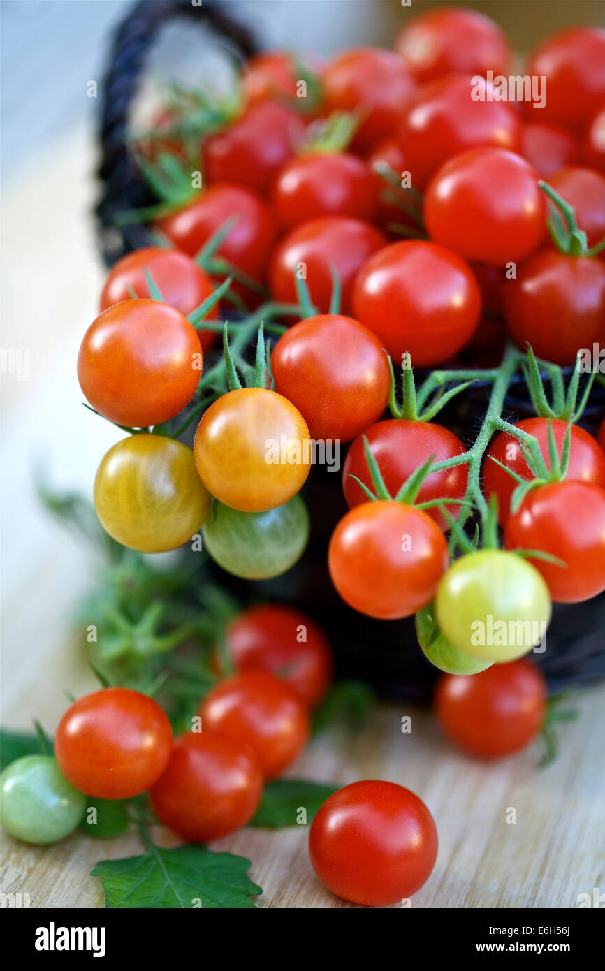 Cherry tomatoes in a basket on a wooden background Stock Photo - Alamy