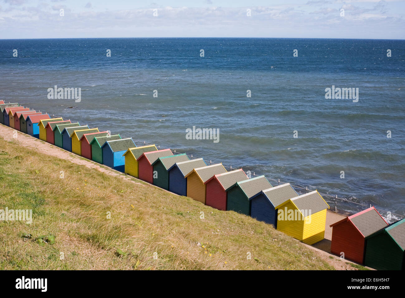Brightly coloured beach huts on the sea front at Whitby, Yorkshire, UK. Stock Photo