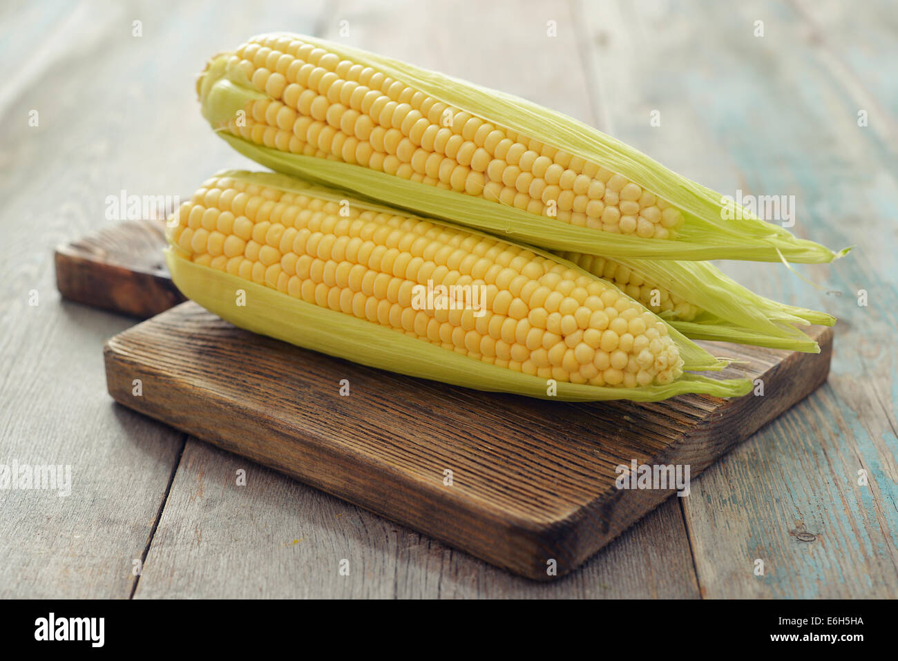 Raw corn cobs on wooden background closeup Stock Photo