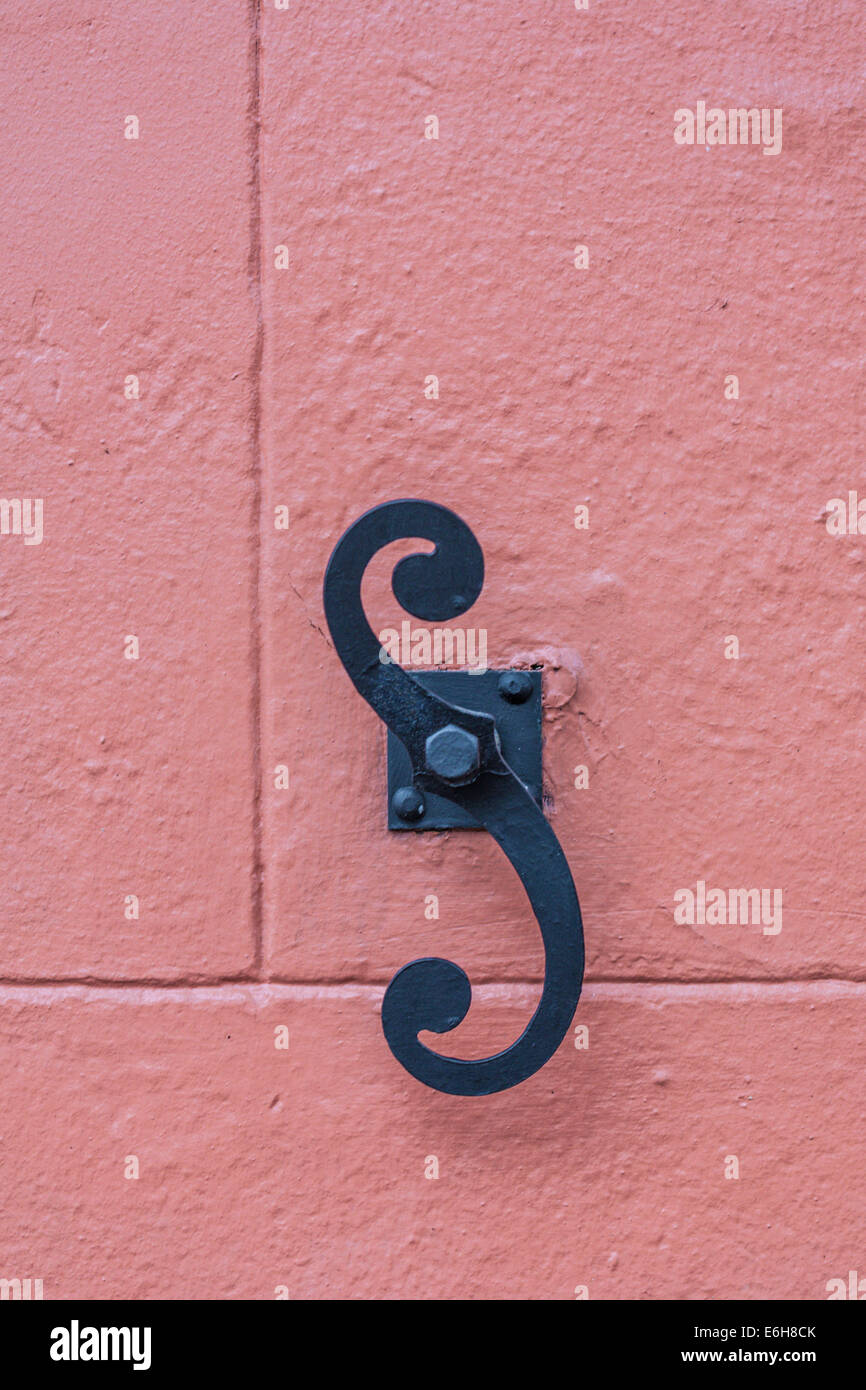 Black antique shutter dog on mauve painted concrete wall in the French Quarter of New Orleans, Louisiana Stock Photo