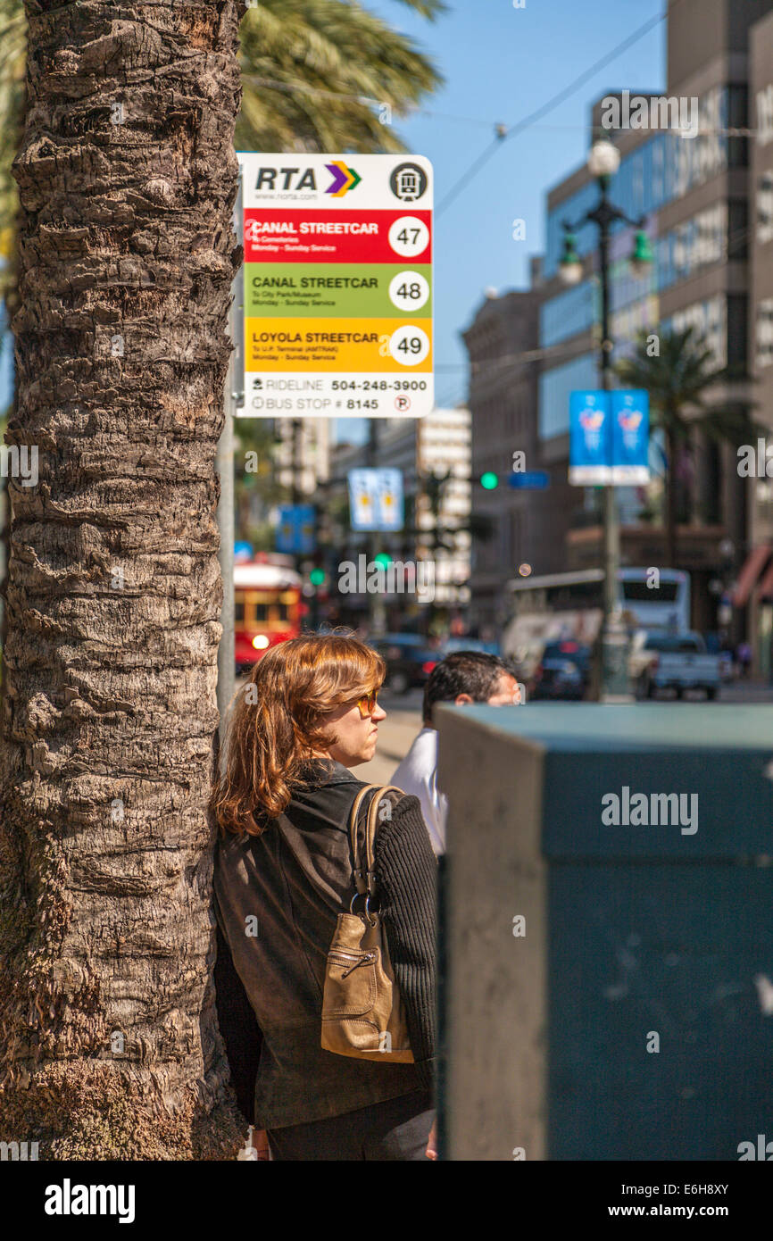 Woman waits at streetcar stop on Canal Street in downtown New Orleans, Louisiana Stock Photo