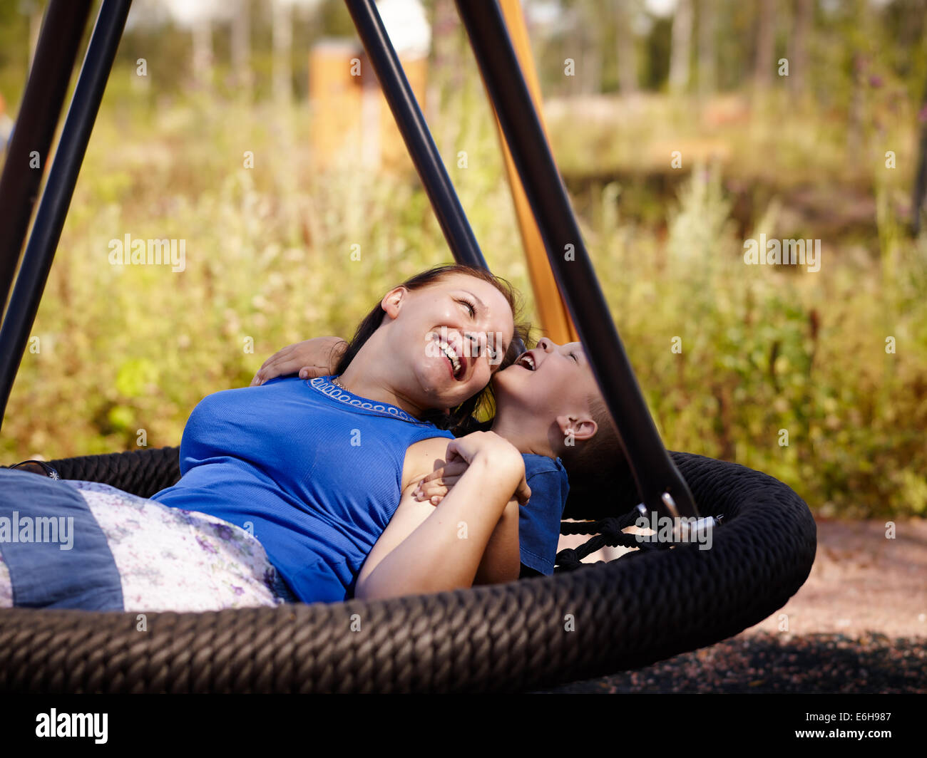 Mother and six year old boy child sitting together on the swing Stock Photo