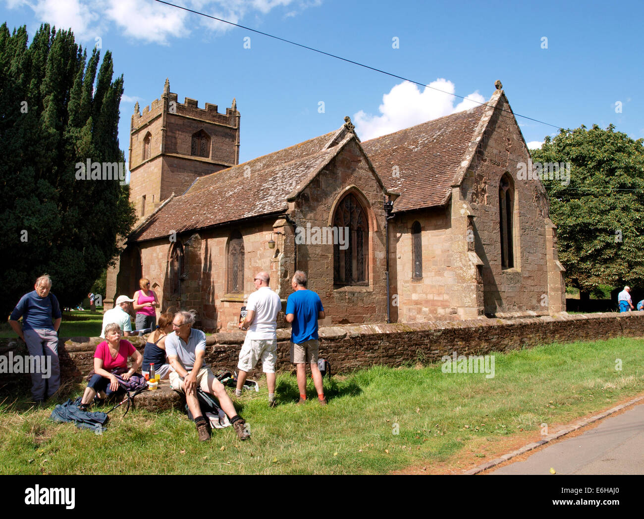 Group of walkers stopped for lunch beside St. Martin's Church, Holt, Worcestershire, UK Stock Photo