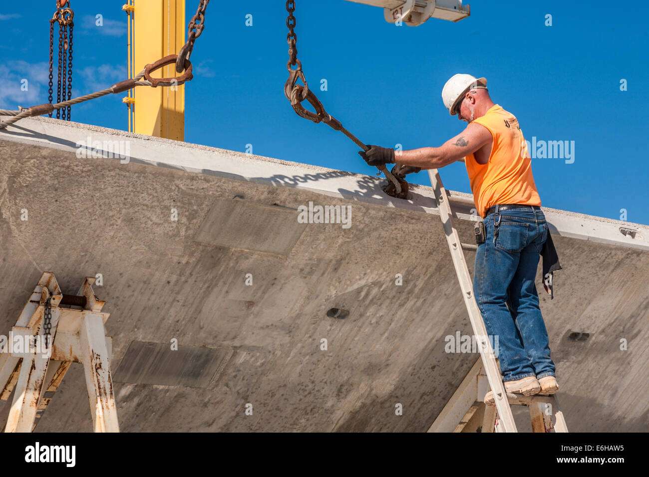 Hooker places crane hooks on precast concrete wall panel for loading onto truck Stock Photo