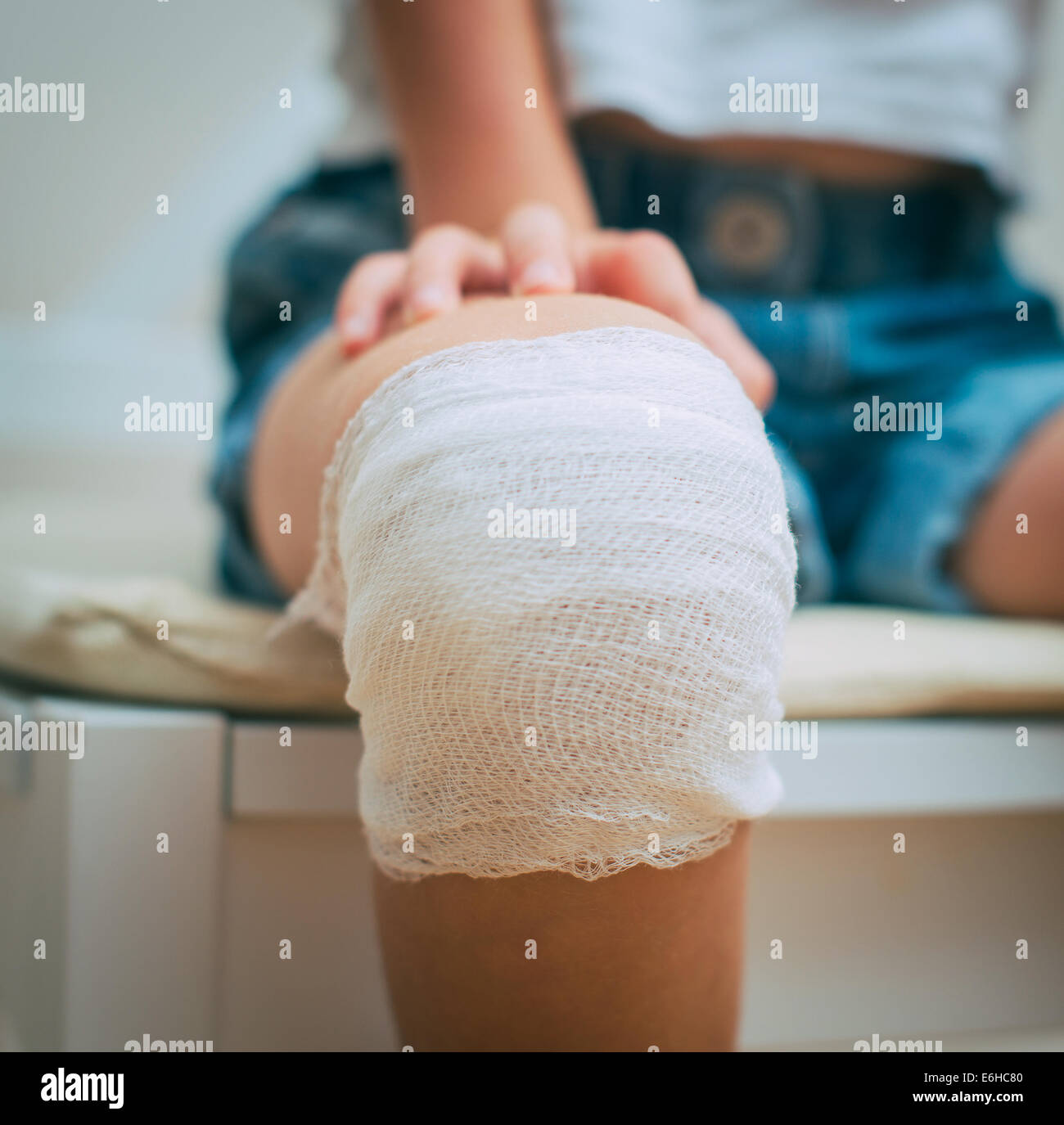 Child knee with adhesive and gauze bandage. Stock Photo