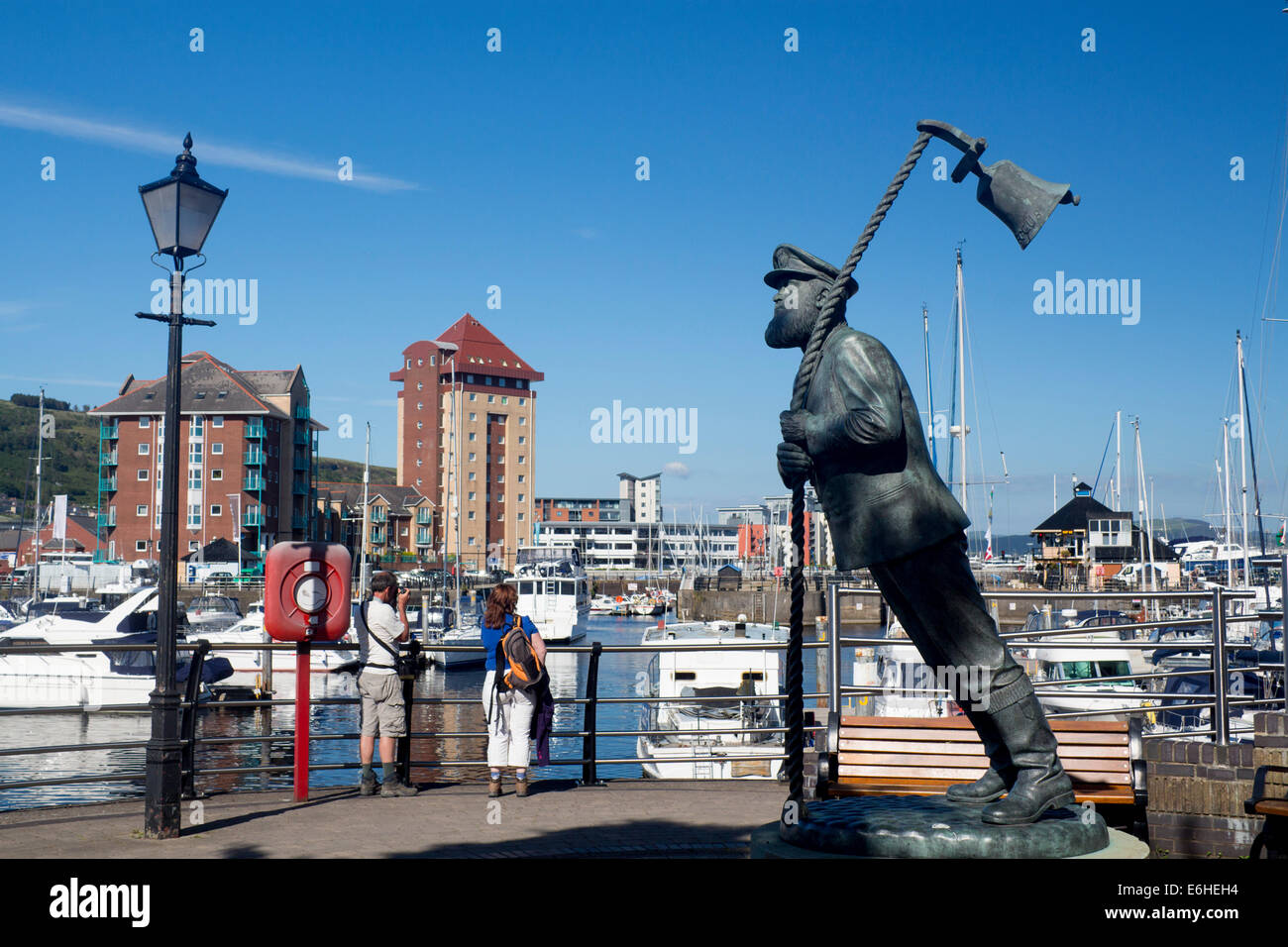 Captain Cat statue (Dylan Thomas Under Milk Wood character) with tourists taking photographs behind Swansea Marina Wales UK Stock Photo