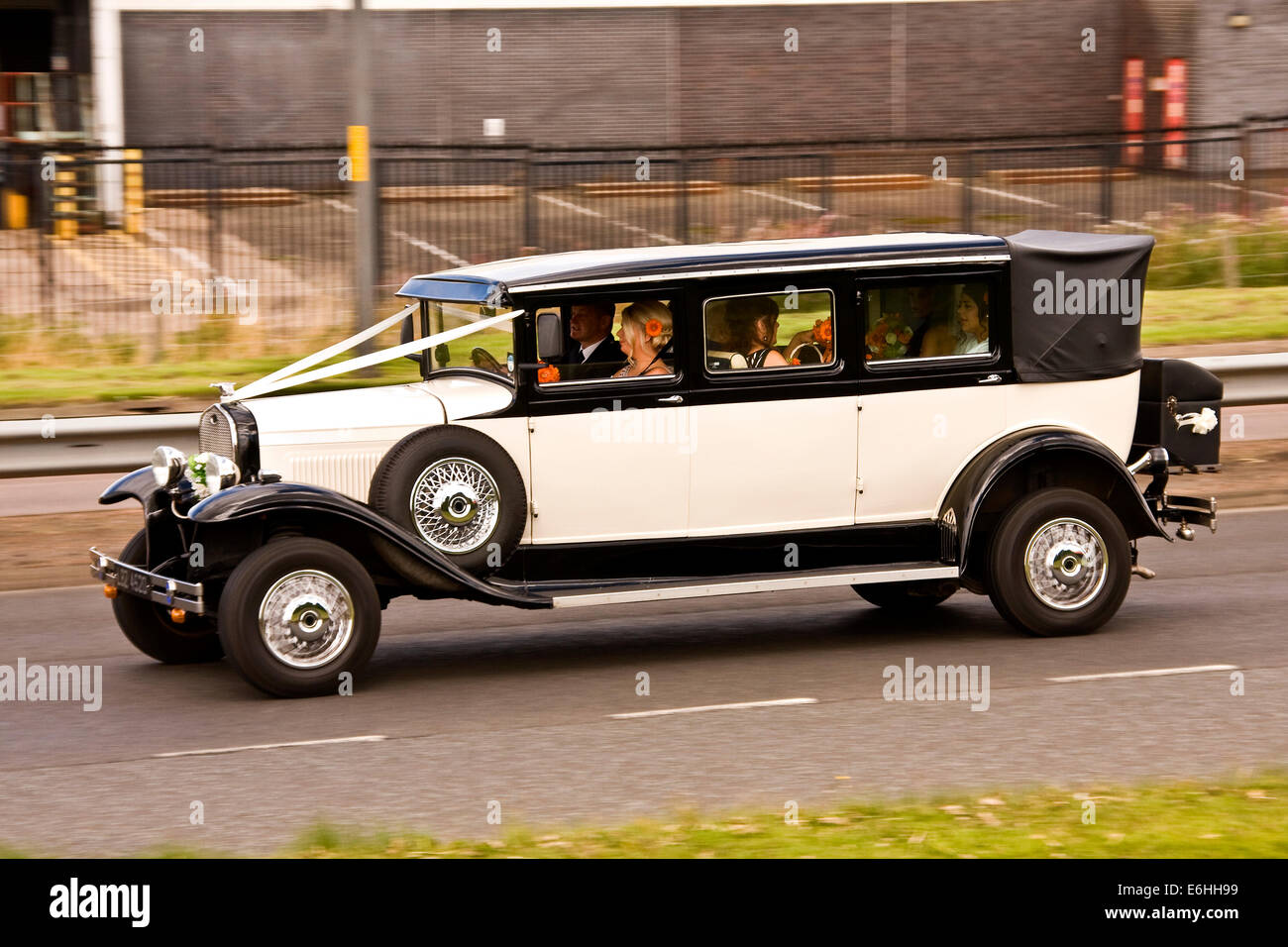 Panning a vintage Wedding limousine full of Bridesmaids travelling along the Kingsway West Dual Carriageway in Dundee, UK Stock Photo