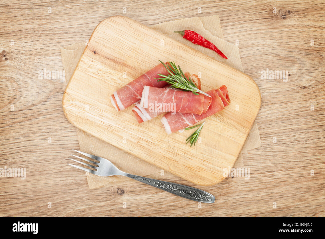Prosciutto with spices. Over wooden table background Stock Photo