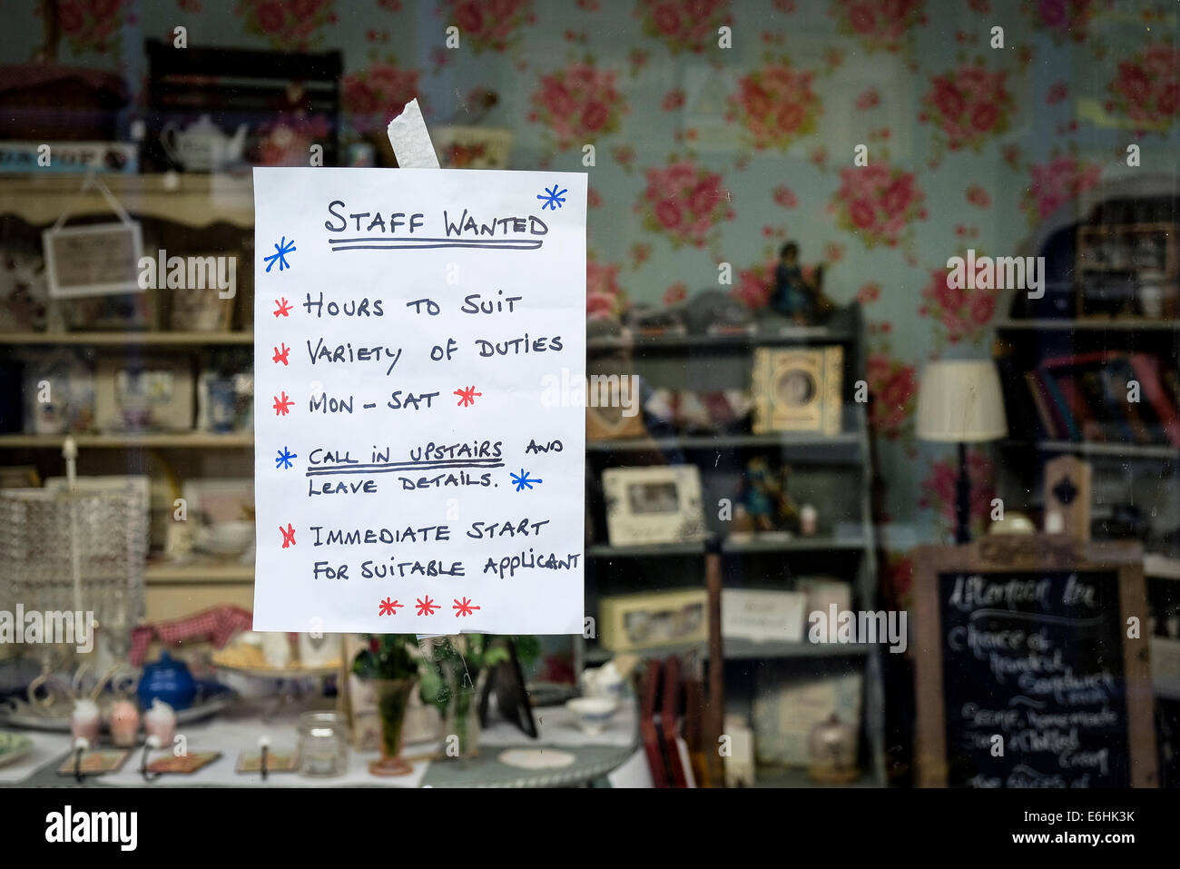 A hand written sign notice in a shop window advertising jobs staff vacancies. Stock Photo