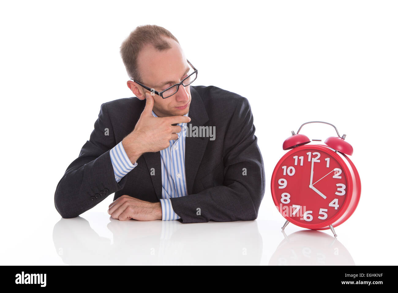 Closing time at four o'clock: isolated businessman looking pensive an unhappy at a red alarm clock. Stock Photo