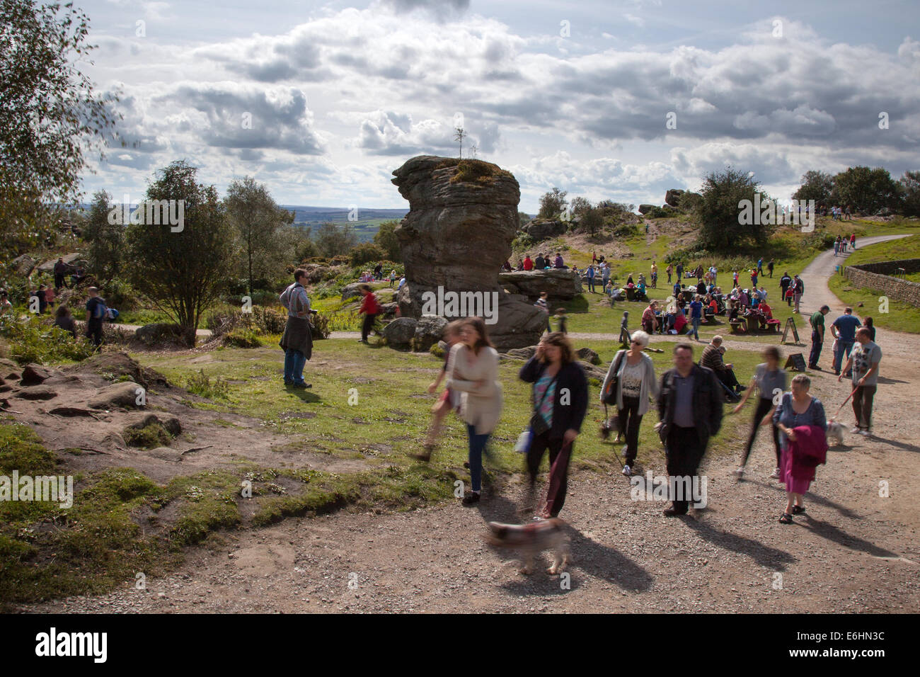 People at Brimham Rocks; Brimham Crags a collection of balancing natural rock formations sculpted over centuries by ice, wind and rain in the North Yorkshire Dales. holidaying active kids and visiting tourists at the National Trust Site making a great day out for families and climbers enjoying  a peculiar set of rock formations composed of millstone grit shaped by wind and weather Stock Photo