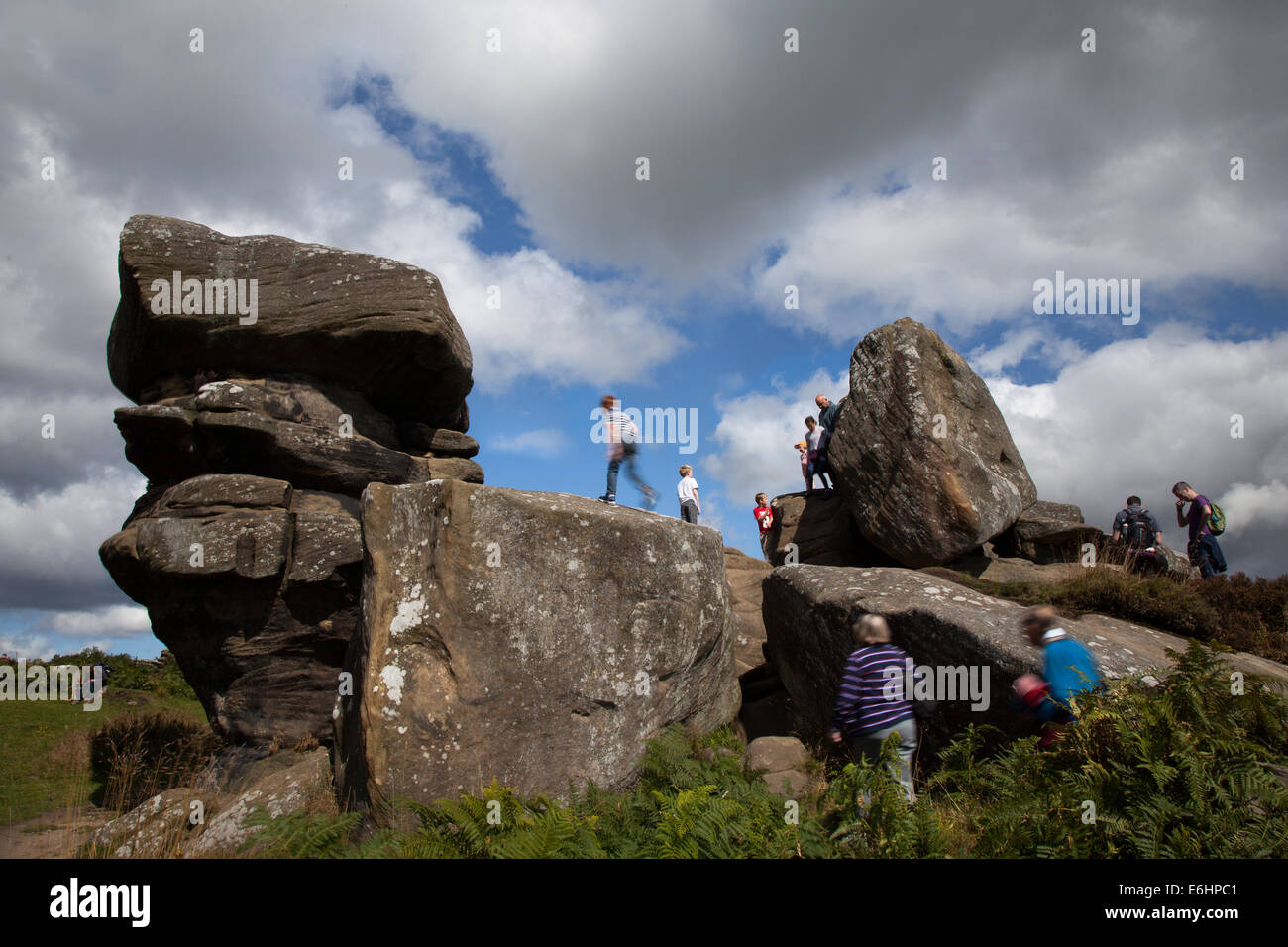 People at Brimham Rocks; Brimham Crags a collection of balancing natural rock formations sculpted over centuries by ice, wind and rain in the North Yorkshire Dales. holidaying active kids and visiting tourists at the National Trust Site making a great day out for families and climbers enjoying  a peculiar set of rock formations composed of millstone grit shaped by wind and weather Stock Photo