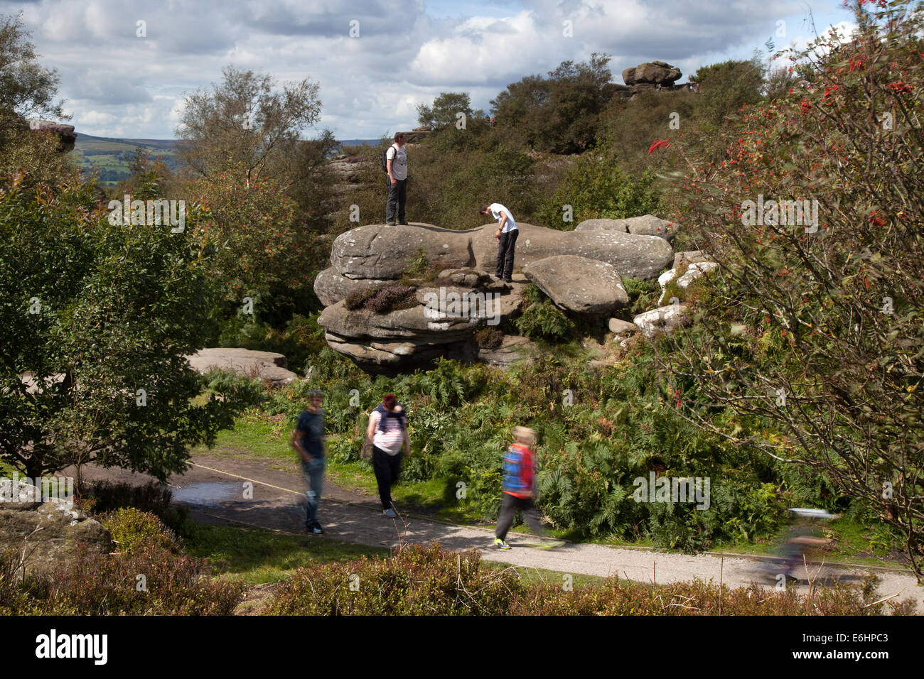 People at Brimham Rocks; Brimham Crags a collection of balancing natural rock formations sculpted over centuries by ice, wind and rain in the North Yorkshire Dales. holidaying active kids and visiting tourists at the National Trust Site making a great day out for families and climbers enjoying  a peculiar set of rock formations composed of millstone grit shaped by wind and weather Stock Photo