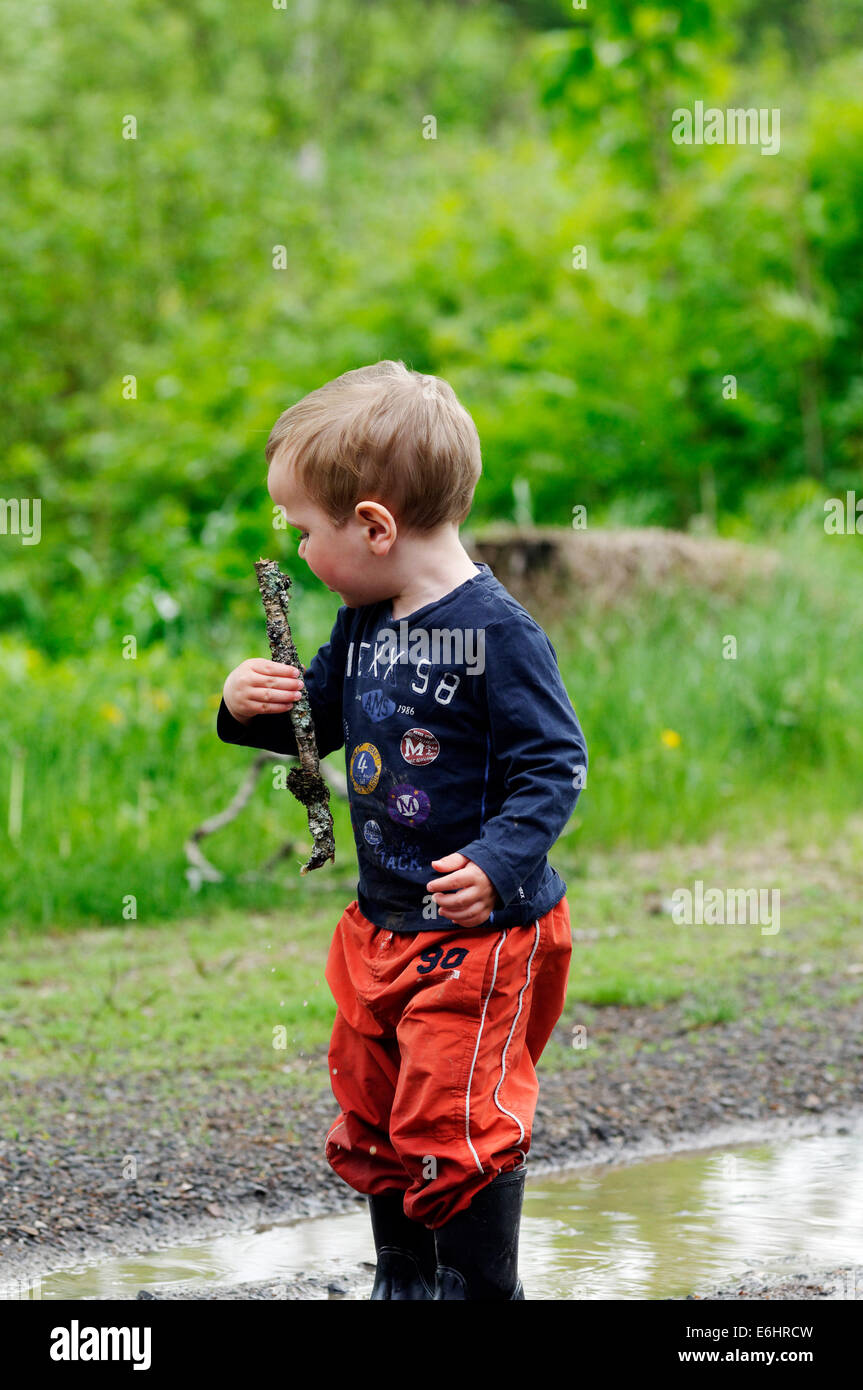 A young boy getting soaked running through a puddle Stock Photo