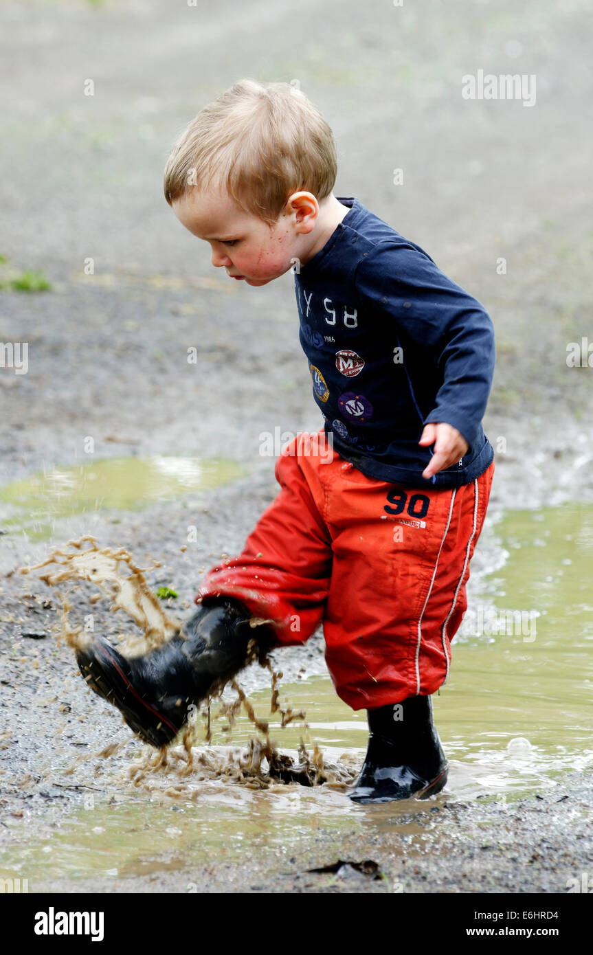 A young boy getting soaked running through a puddle Stock Photo