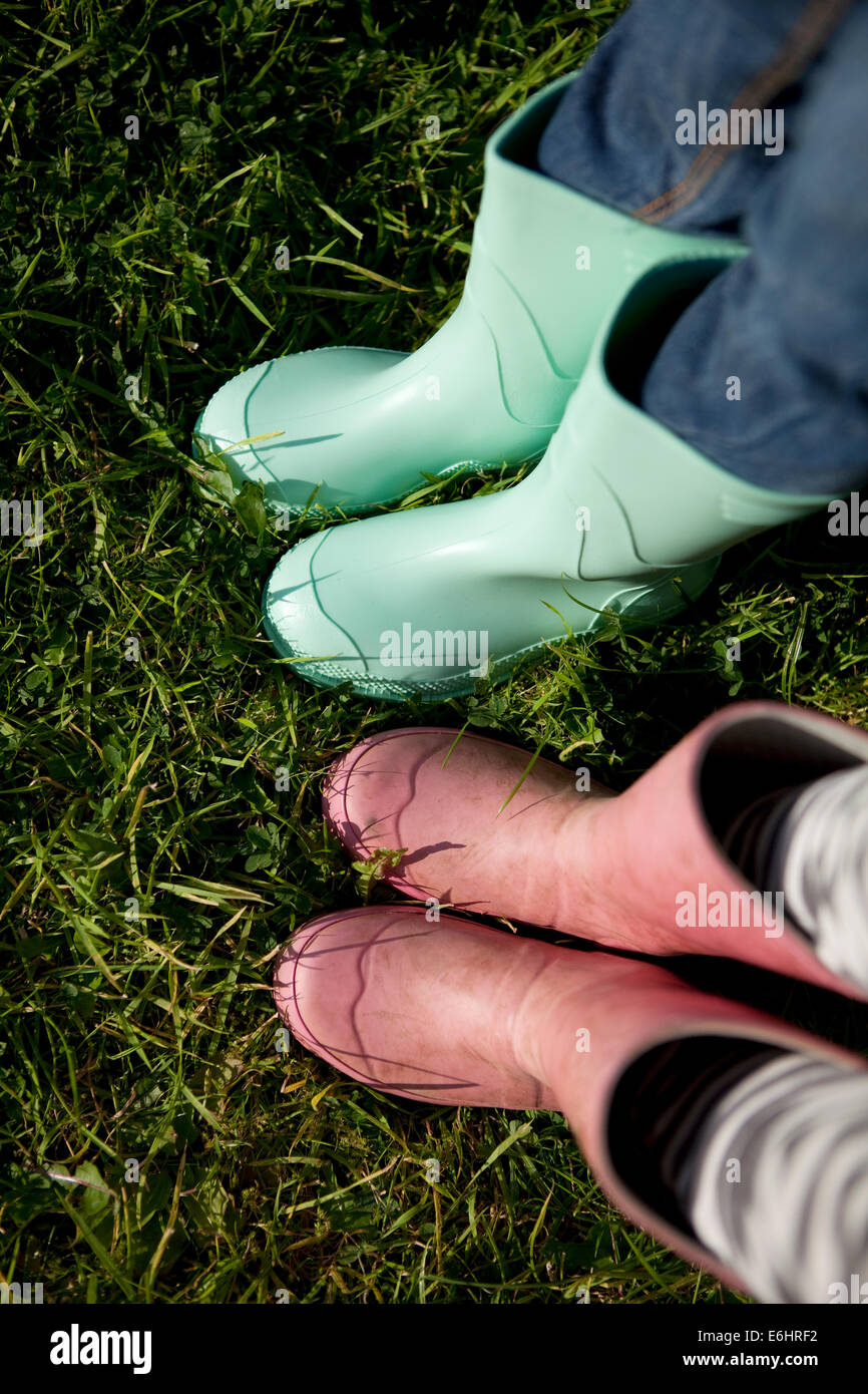 'Point of view' of children wearing wellington boots on grass. Stock Photo