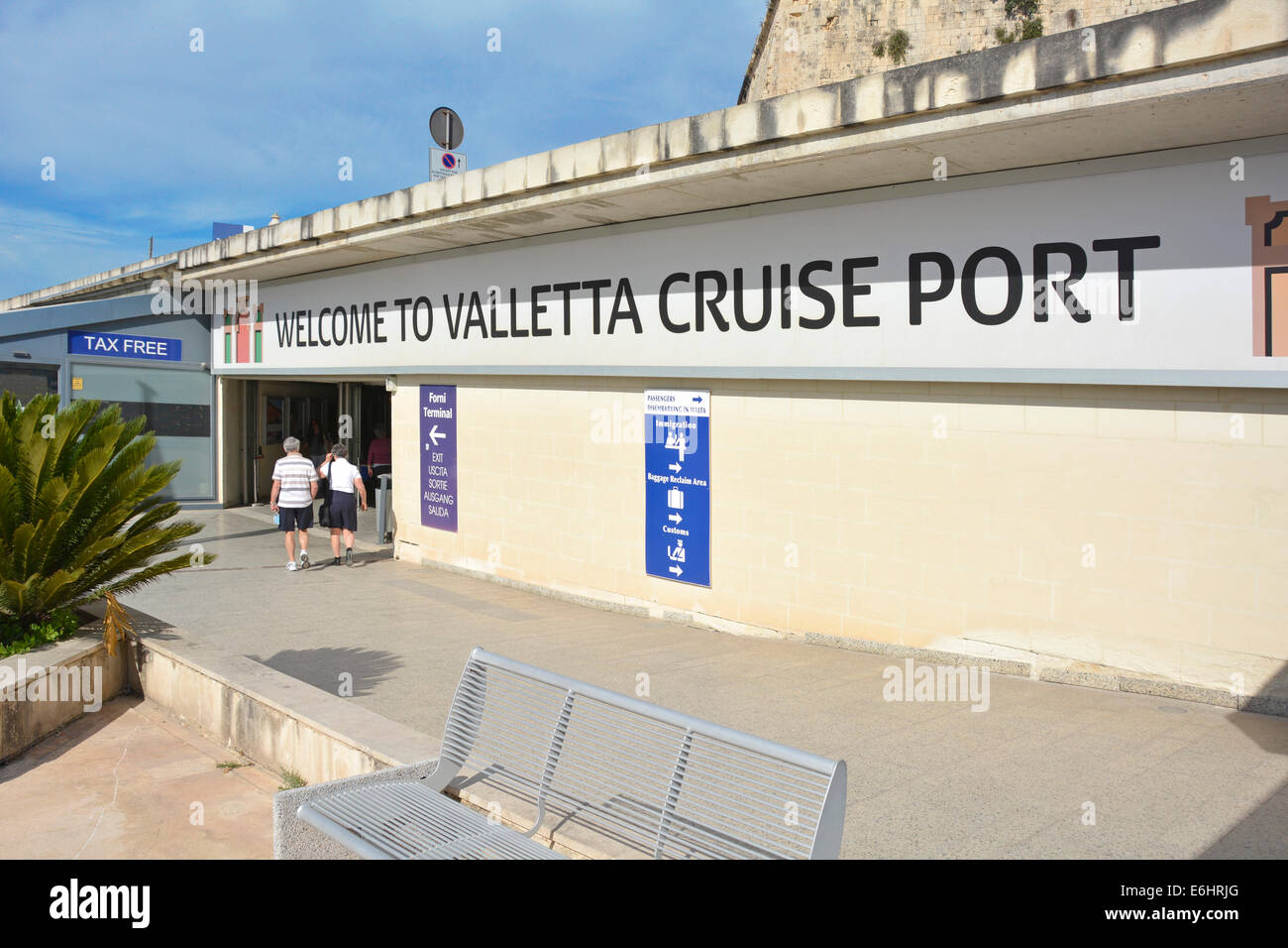Couple from liner walking below 'Welcome to Valletta Cruise Port' sign in the Grand Harbour Malta Stock Photo