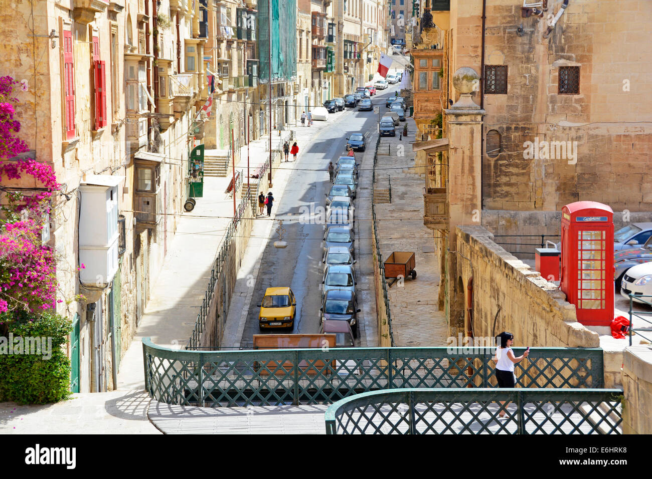 Typical one way residential street with parked cars in the capital city of Valletta Malta including British red phone box Stock Photo