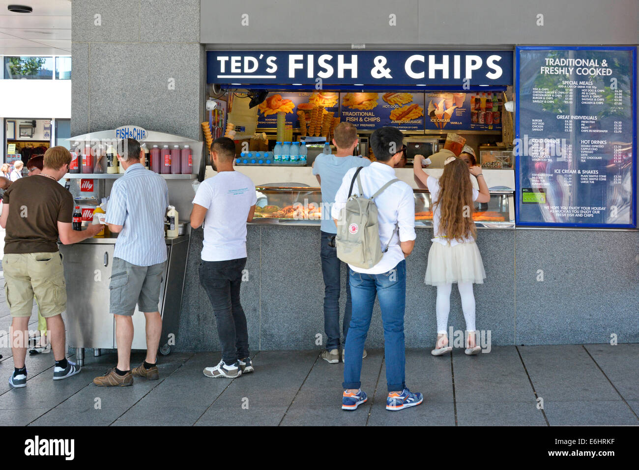Teds Fish and Chips shop counter back view tourist group customers shopping for traditional British food by people visiting Tower of London England UK Stock Photo
