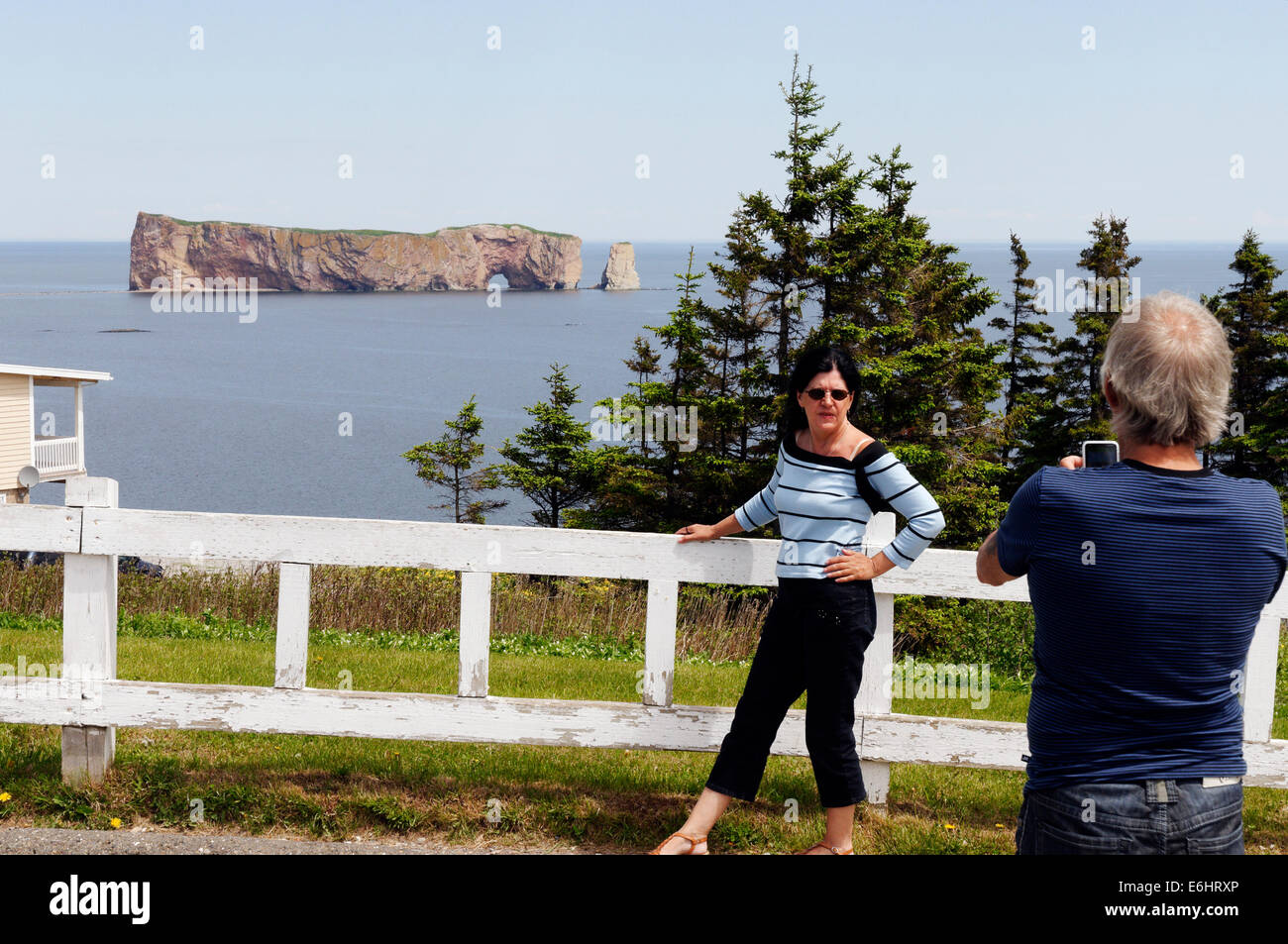 A man taking pictures of his wife and the Rocher Percé in Gaspesie, Quebec Stock Photo