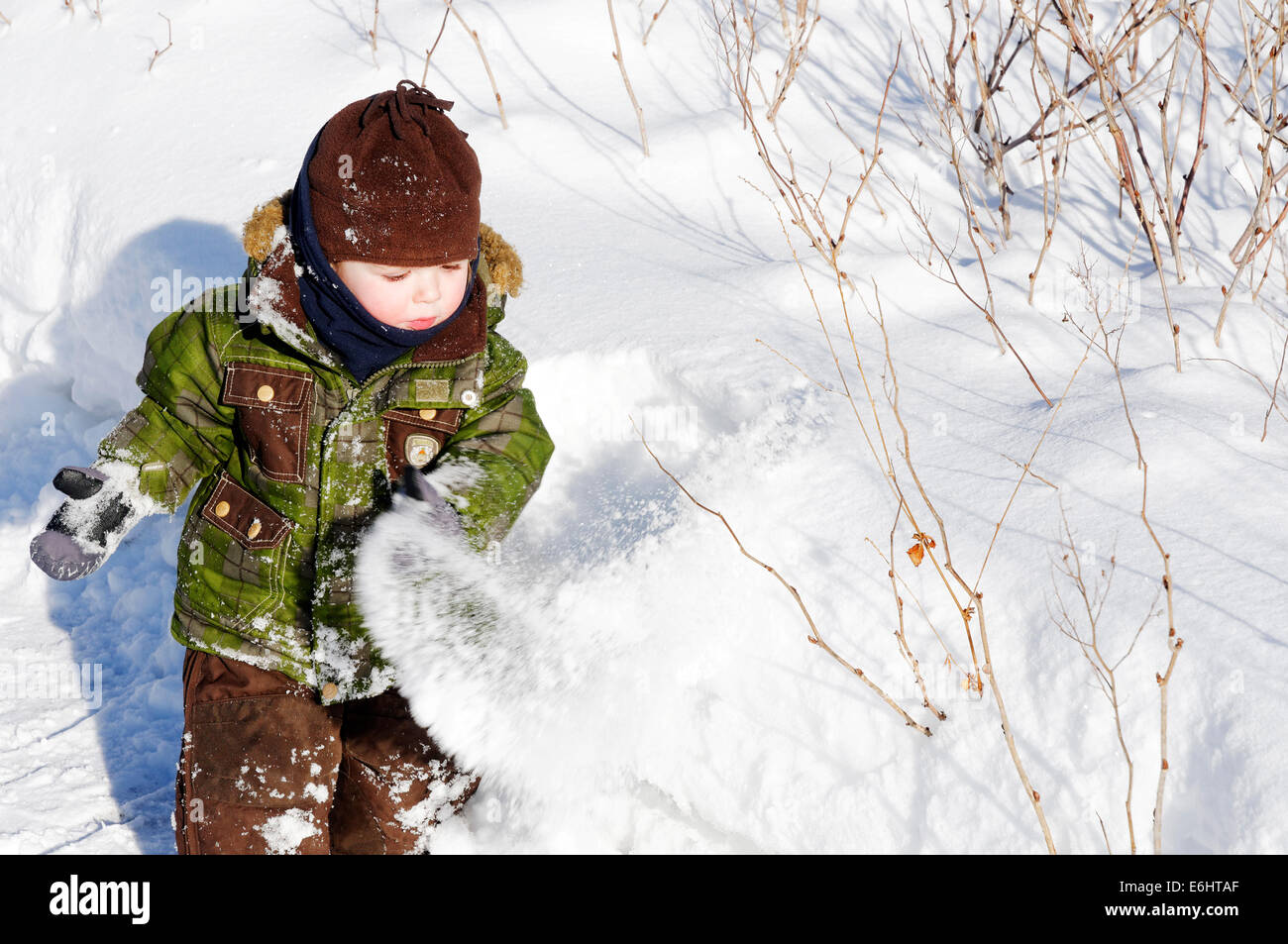 A 2 year old boy playing with fresh snow in Quebec Canada Stock Photo