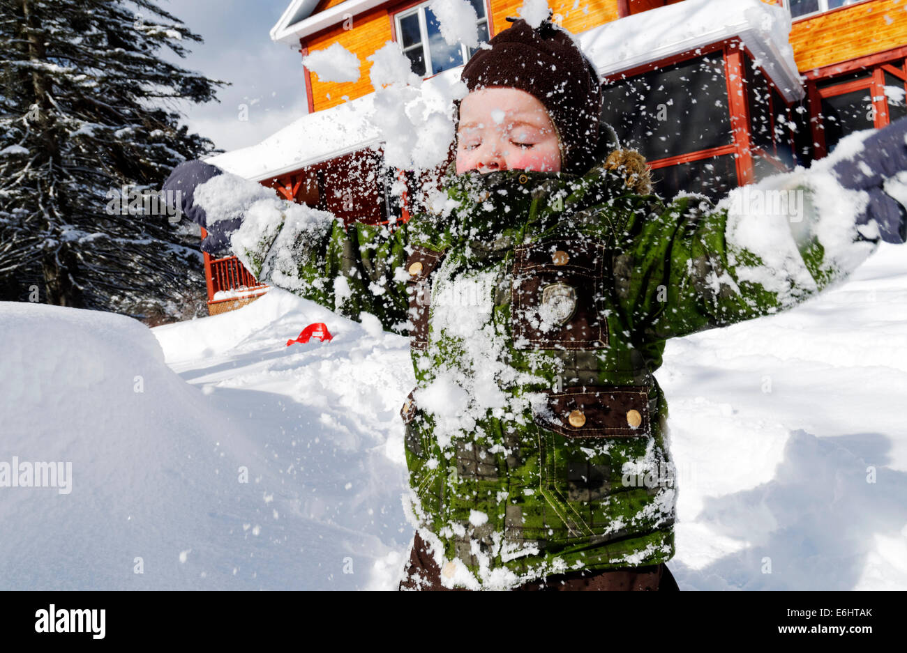 A 2 year old boy playing with fresh snow in Quebec Canada Stock Photo