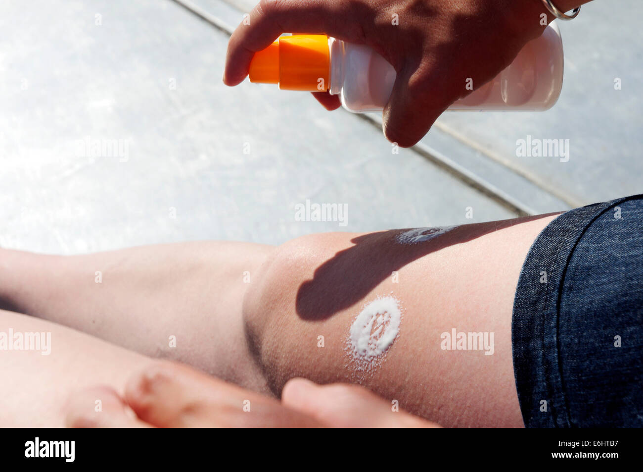 A woman putting sun cream on her legs Stock Photo