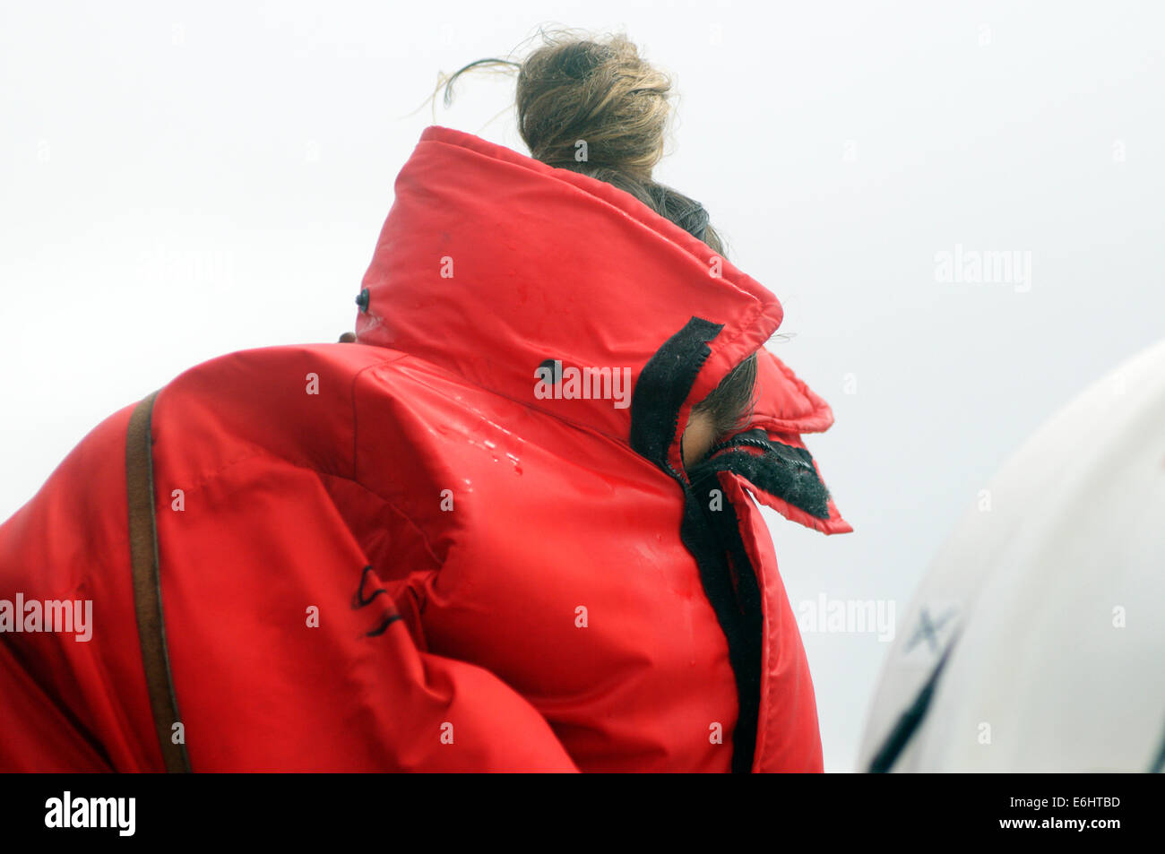 Amiserable woman trying to hide from freezing cold spray on a whale watching boat ride on the St Lawrence Stock Photo