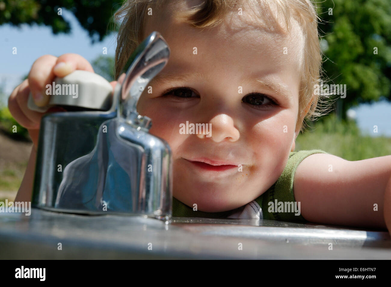 A young boy playing with a drinking water fountain Stock Photo