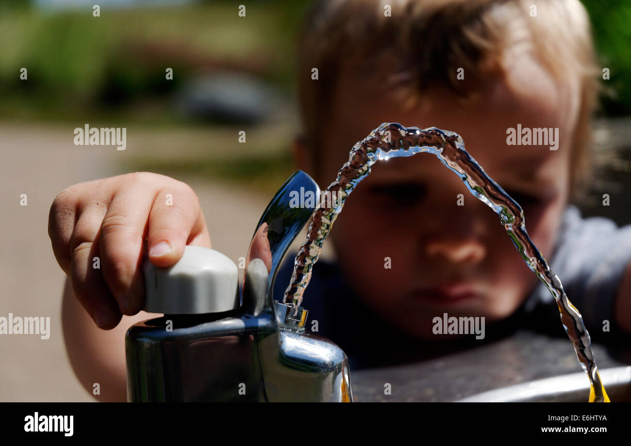 A young boy playing with a drinking water fountain Stock Photo