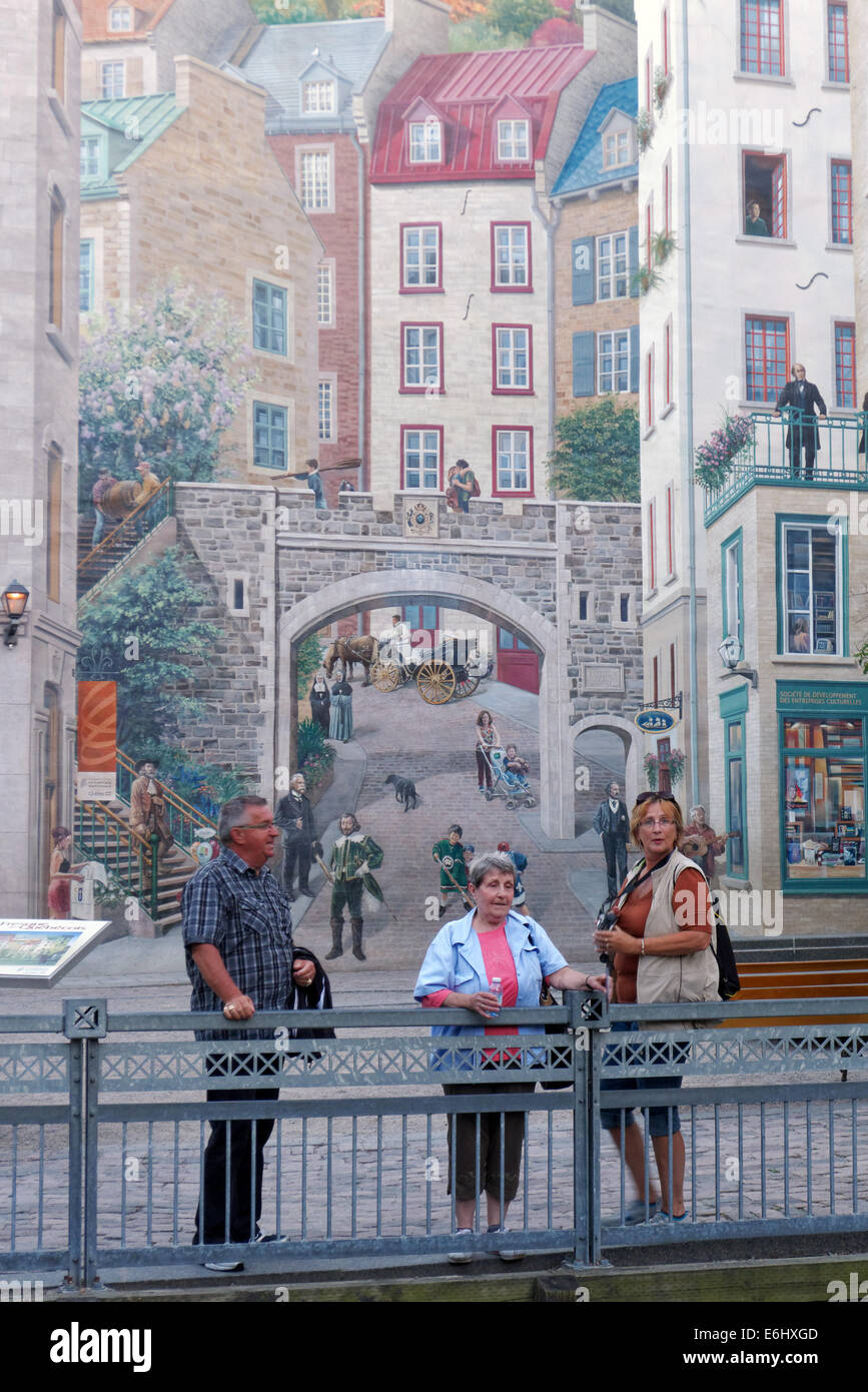 Three tourists in front of a wall mural in Quebec City old town Stock