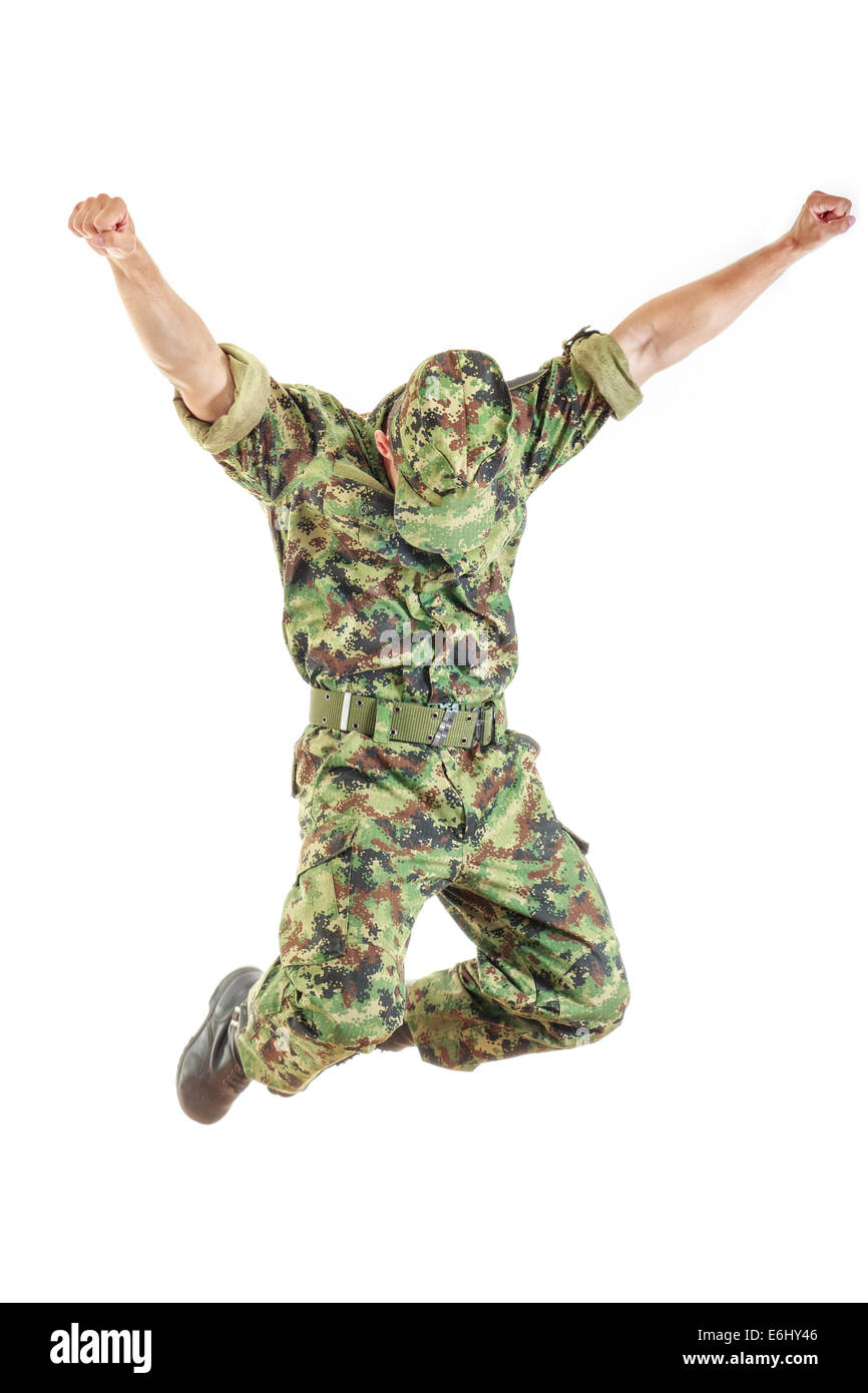 unknown soldier with hidden face in green camouflage uniform and hat jumping up in air with both hands raised above as sign of s Stock Photo